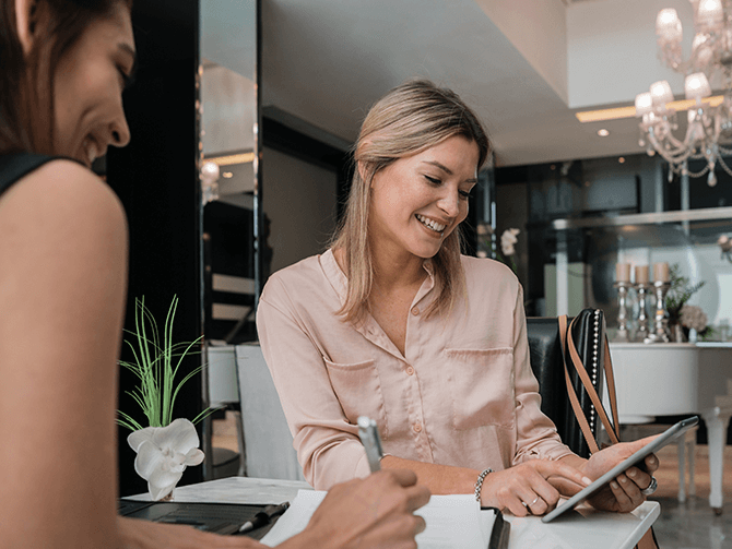 Zwei lächelnde Frauen schauen etwas am iPad an